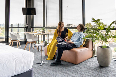 a couple of students sitting on a couch in a spacious room with a great city view 