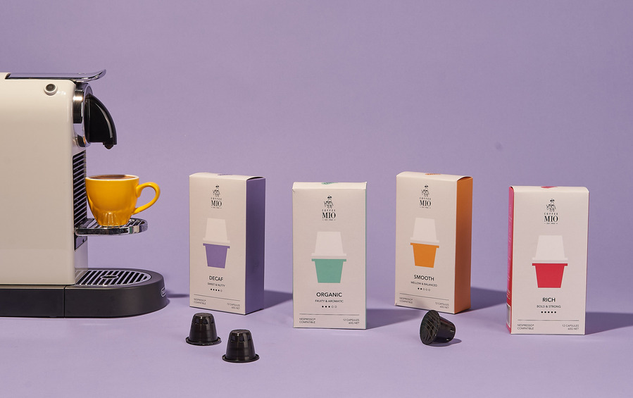 Modern espresso machine with brightly packaged coffee pods and lavender backdrop