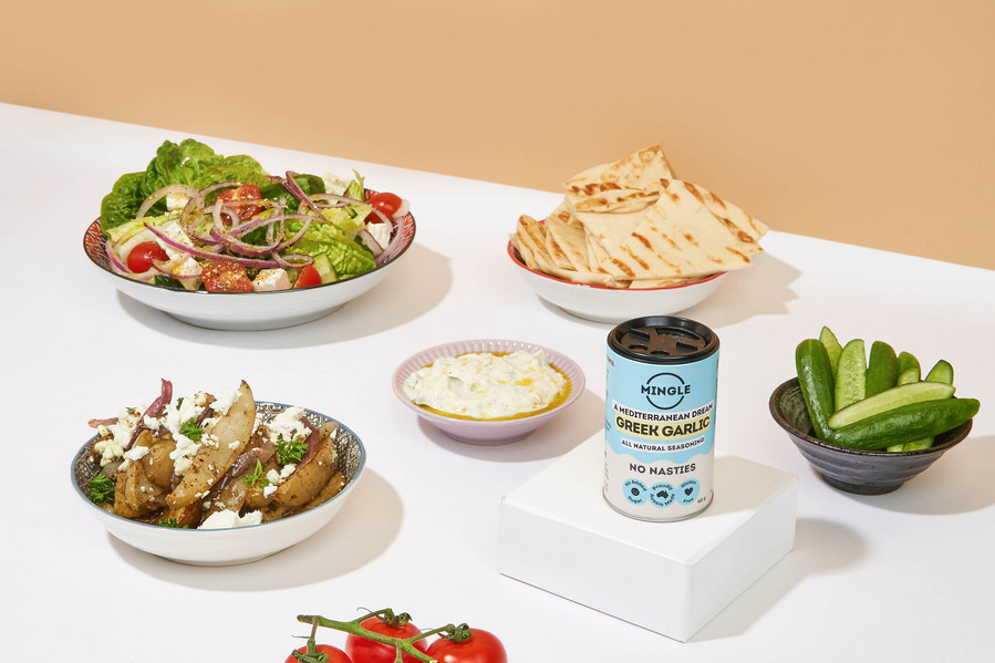 spice can on a white plinth with food items such as a salad bowl, roasted potatoes lying next to it