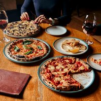 Table with artisan pizzas and wine glasses by Marcie Raw, Melbourne food and lifestyle photographer