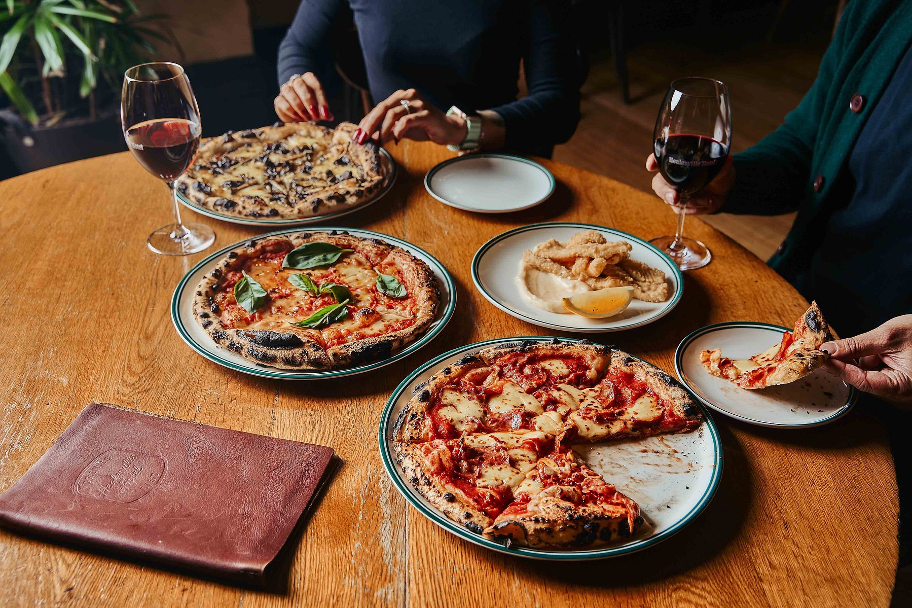 Table with artisan pizzas and wine glasses by Marcie Raw, Melbourne food and lifestyle photographer