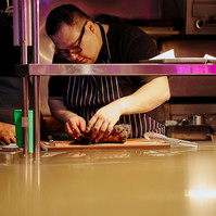 Chef plating gourmet dish in restaurant kitchen by Marcie Raw, Melbourne food photographer