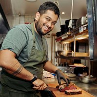 Chef slicing meat in kitchen — Marcie Raw Melbourne chef portrait