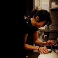  Female chef working in dimly lit kitchen plating food — Melbourne hospitality and chef portrait photography