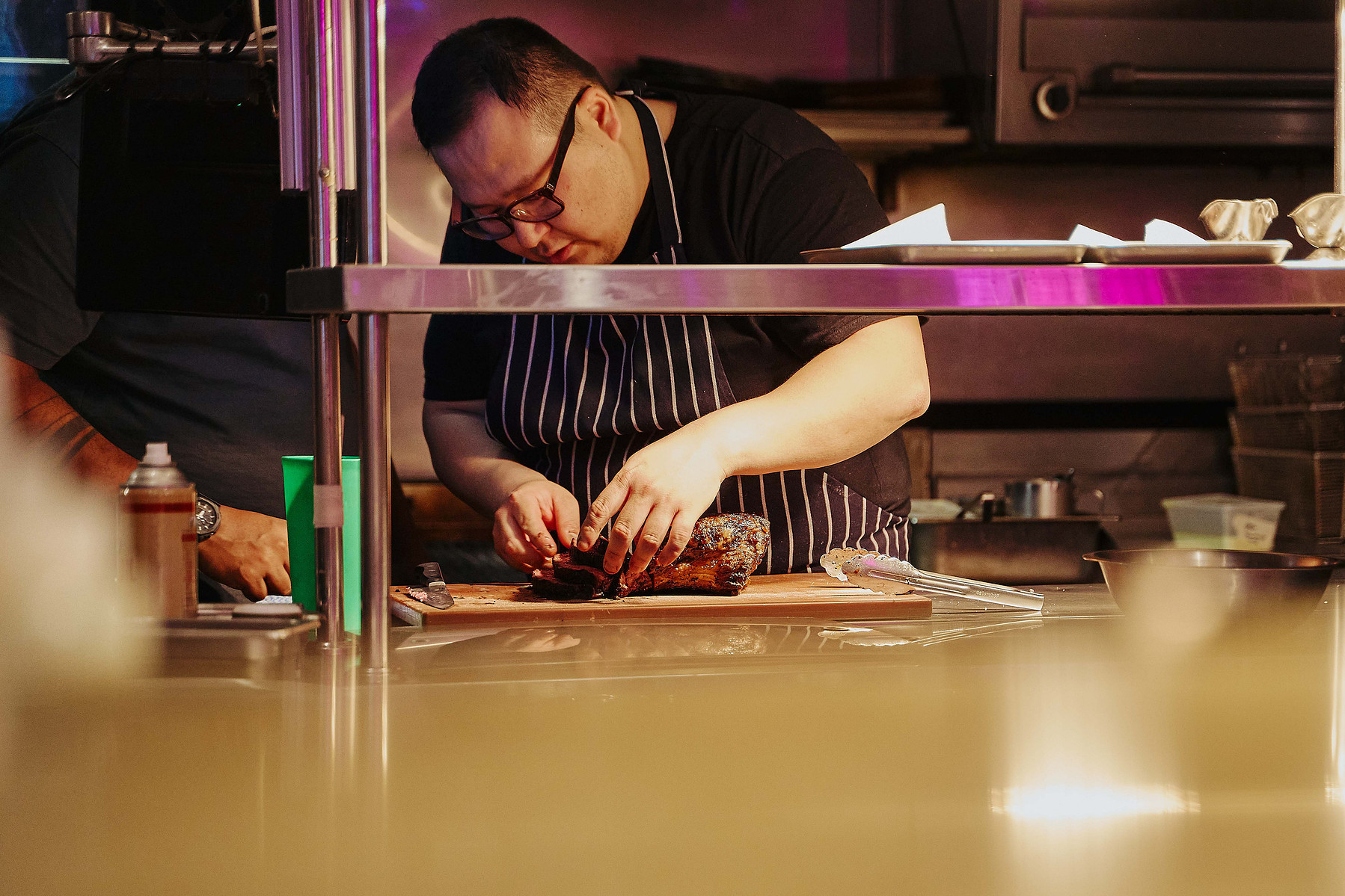 Chef plating gourmet dish in restaurant kitchen by Marcie Raw, Melbourne food photographer