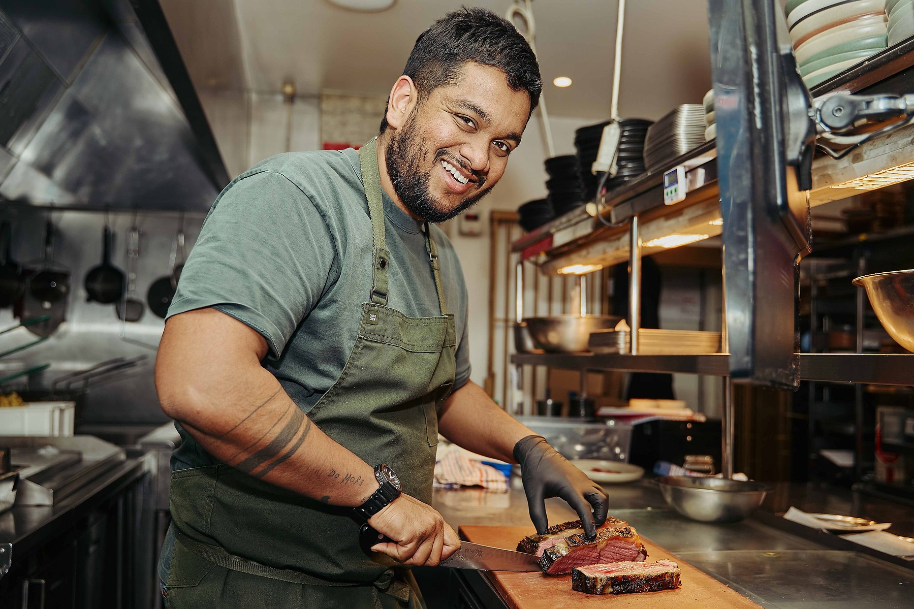 Chef slicing meat in kitchen — Marcie Raw Melbourne chef portrait