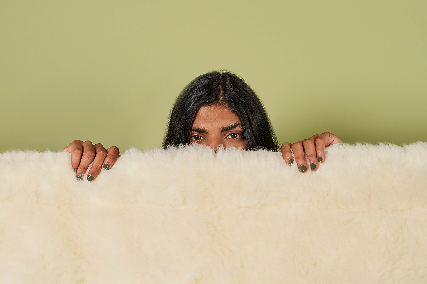 Woman holding fluffy wool rug in front of green background — Melbourne lifestyle product photographer