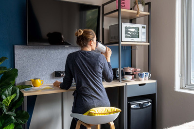 a student sitting in a room drinking coffee and looking through the window