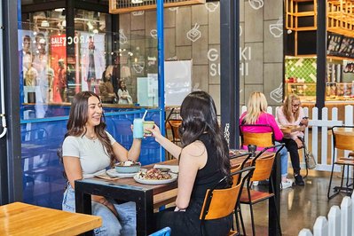 two girls having brunch in a cafe and doing cheers with their smoothies