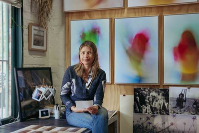 artist in the studio holding a photo and looking at the camera 