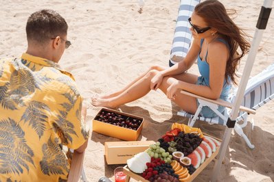 Couple enjoying fruit box on the beach with cherries and grapes – lifestyle food scene by Melbourne photographer Marcie Raw