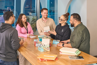 Group of colleagues or friends chatting around a wooden table at a creative workspace in Melbourne, personal branding photography by Marcie Raw