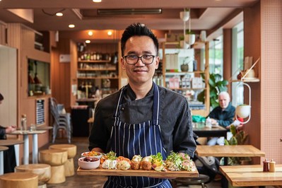 a chef looking at the camera and smiling and presenting a grazing board he's made