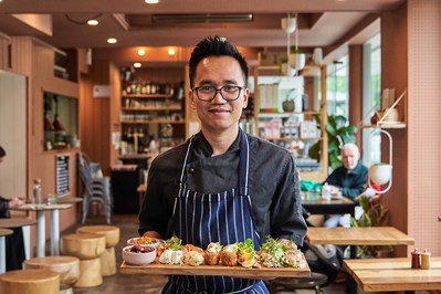 a chef looking at the camera and smiling and presenting a grazing board he's made