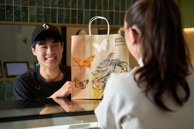 Sushi staff handing takeaway bag to customer – hospitality photography by Marcie Raw, Melbourne