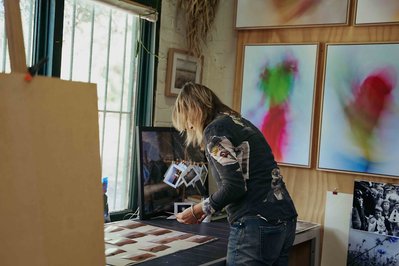 artist in the studio looking at the photos on the desk 