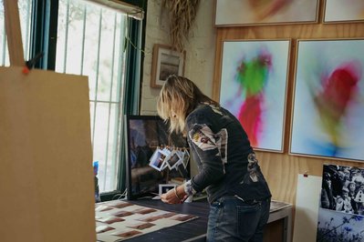 artist in the studio looking at the photos on the desk 