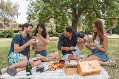 Friends enjoying a gourmet picnic with wine and grazing boxes – lifestyle food photography by Marcie Raw, Melbourne