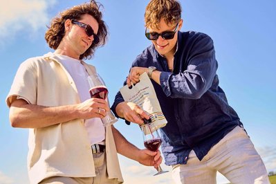 Two men opening wine bottle at vineyard picnic – candid lifestyle photography by Marcie Raw, Melbourne