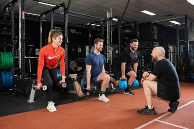 a group of gym members exercising with a trainer