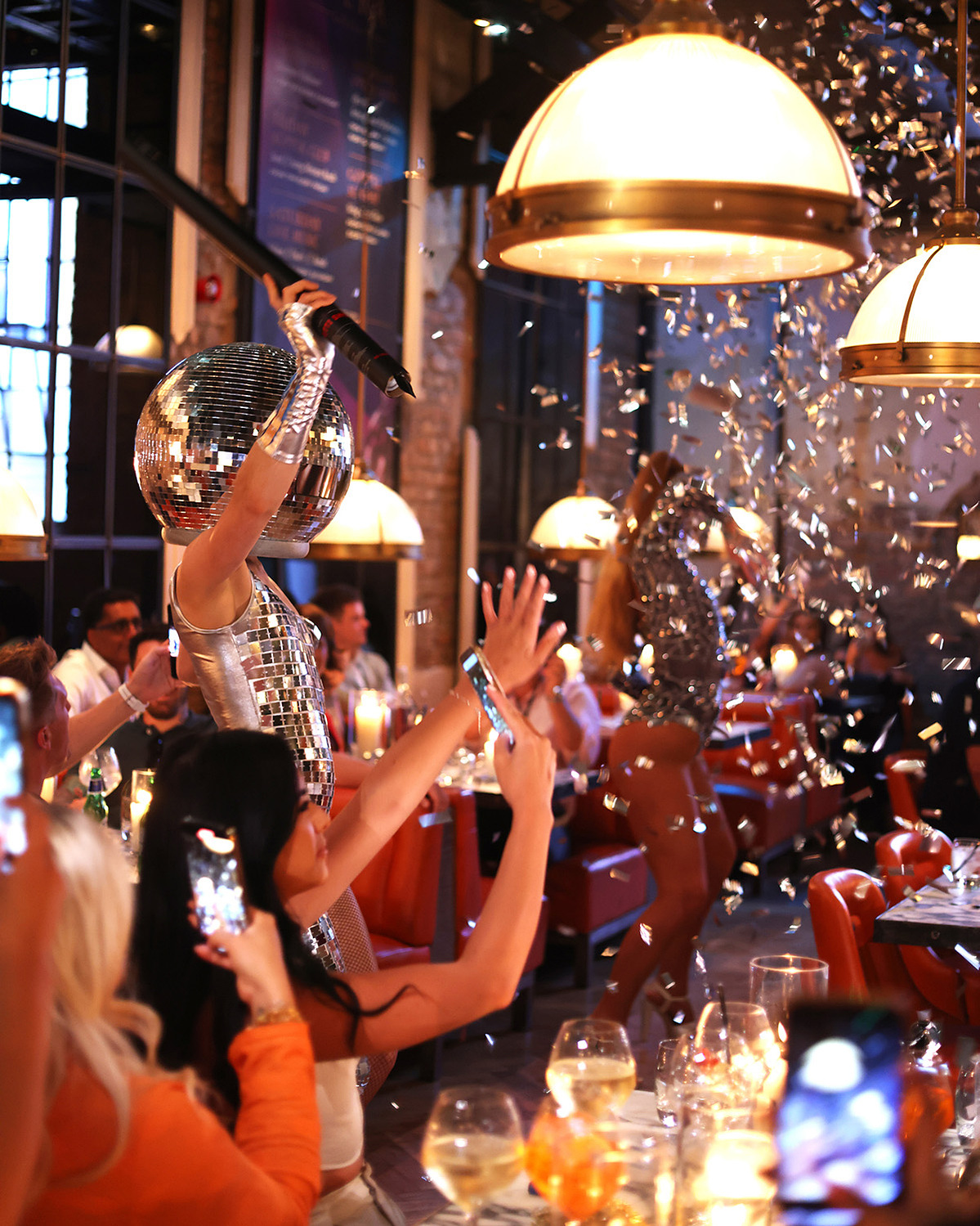 Photograph of a busy party in a restaurant. People taking photos and confetti in the air. Photography by Georgie Glass, Manchester