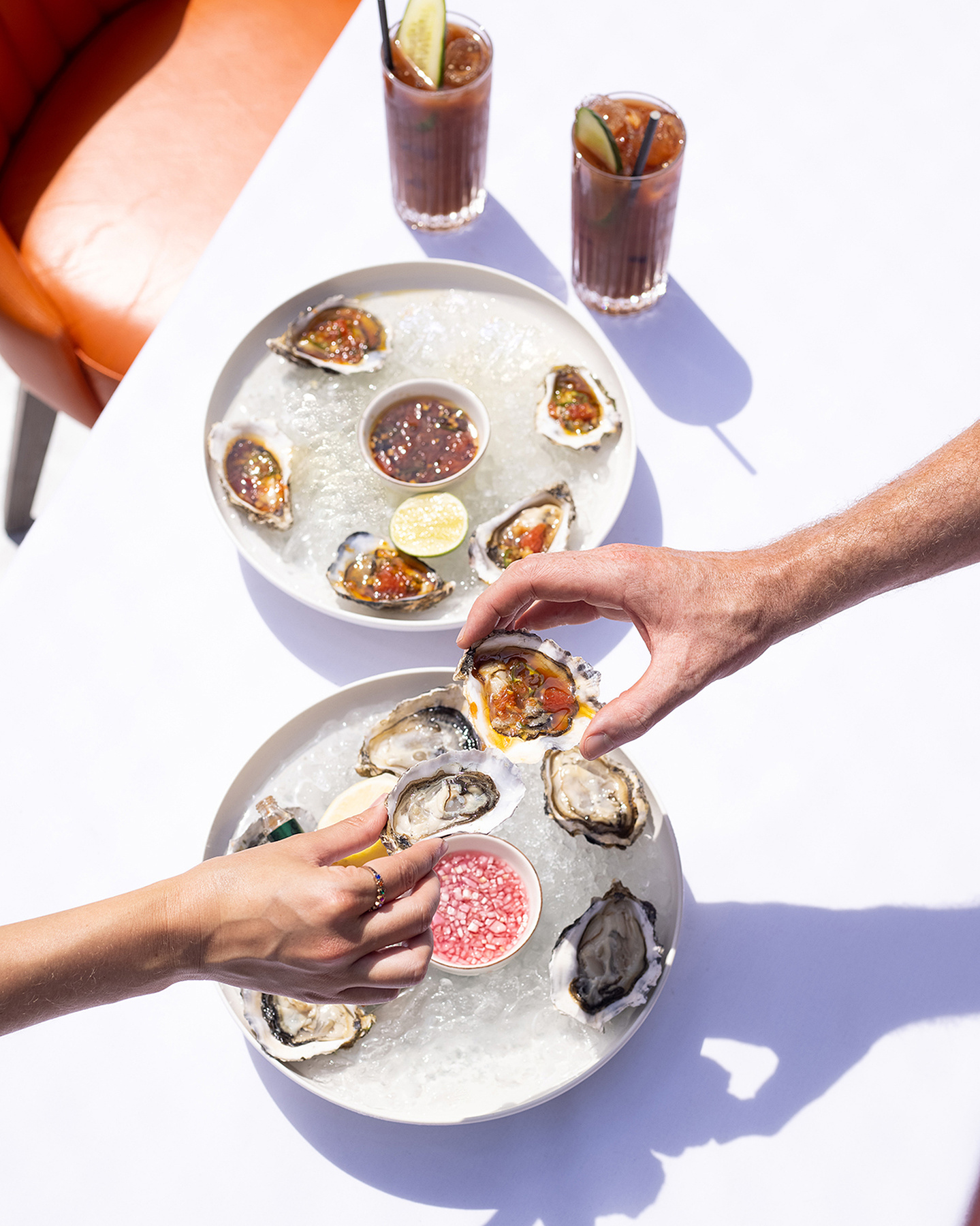 Photo of two hands reaching in to a plate of oysters. photo by Georgie Glass Photography, Manchester