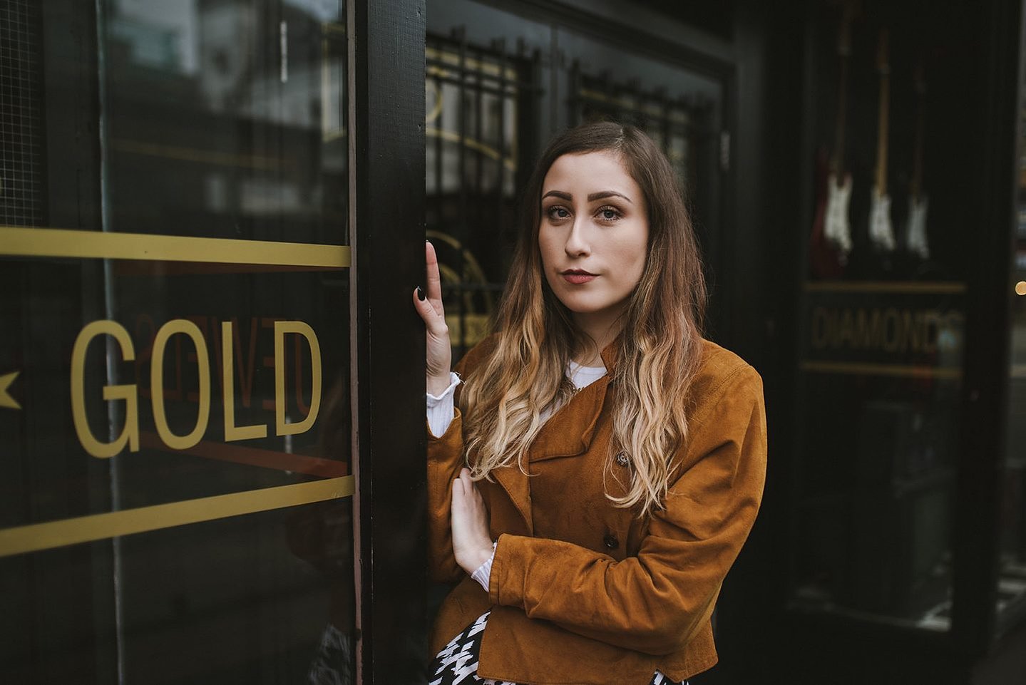 girl stands in Manchester city centres Northern Quarter, wearing a suede jacket and vintage skirt with brown hair