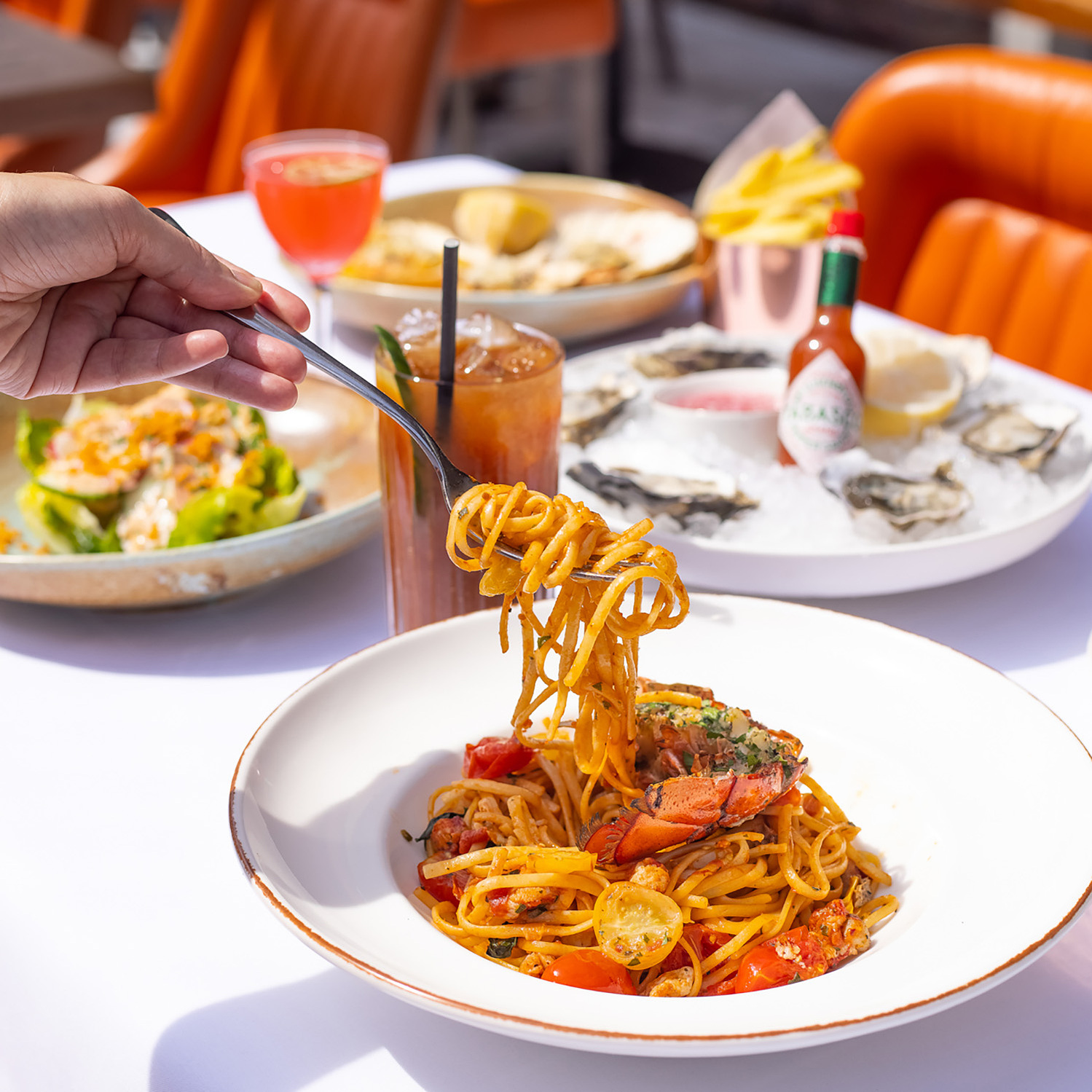 Photo of a restaurant table full of food of plates. Hand folding folk lifting spaghetti. Photography by Georgie Glass, Manchester