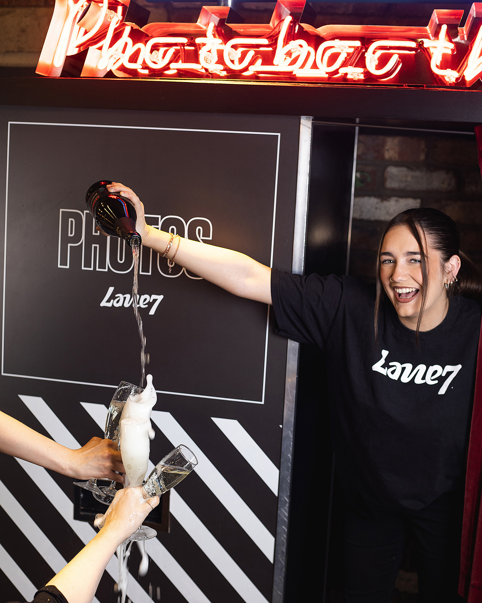 Bar woman laughing as she pours drink into a glass from a height