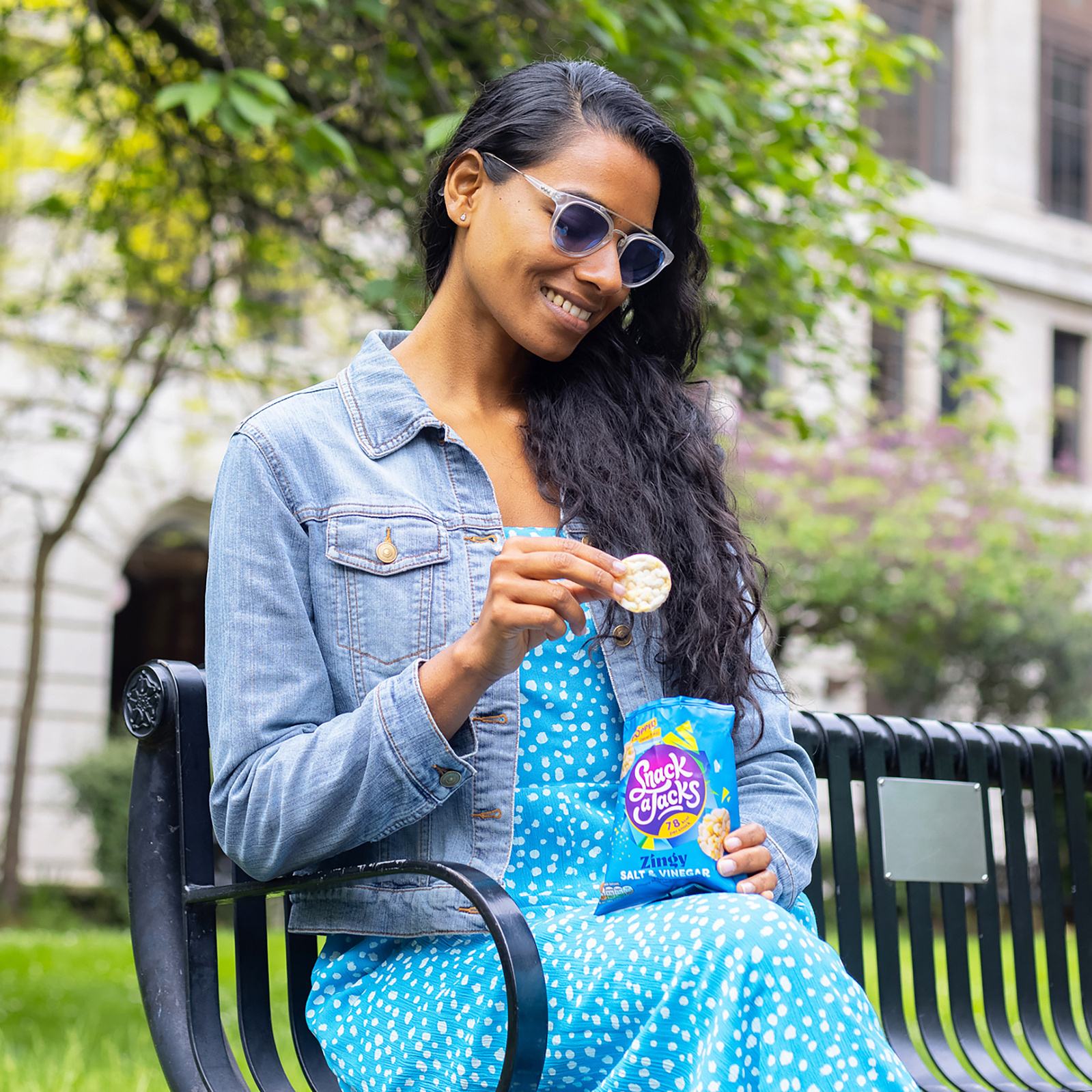 woman sat on park bench eating bag of snack a jacks. photo by Georgie Glass Photography, Manchester