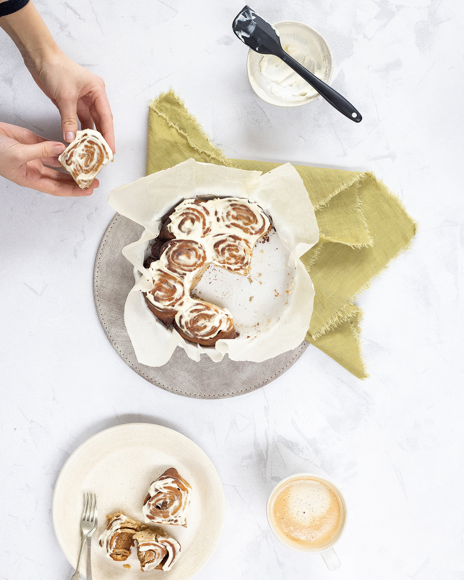 Photo of just baked cinnamon rolls being broken up and put on a plate.