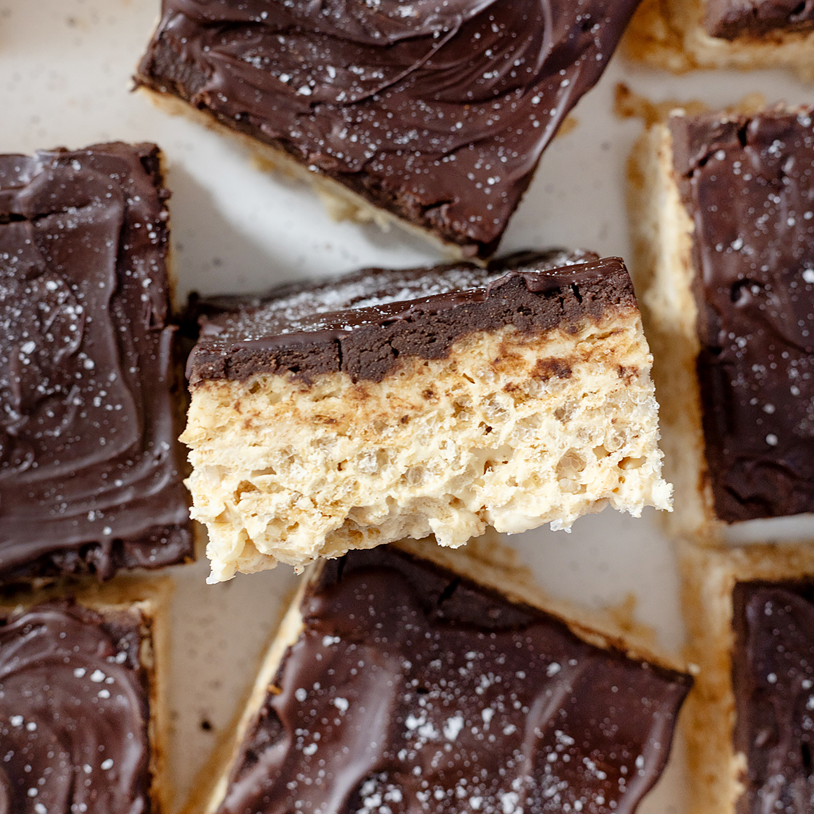 Decadent homemade rice crispy treats topped with a smooth chocolate layer and a sprinkle of sea salt, captured in high detail by Georgie Glass Photography, showcasing the rich textures and indulgent sweetness of the dessert.