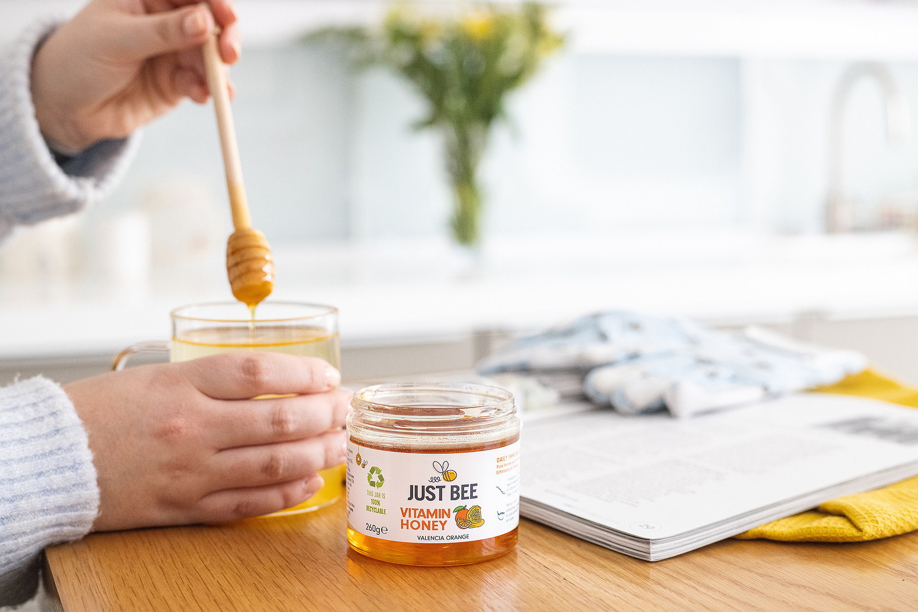 a man drizzling honey from a glass jar into his tea