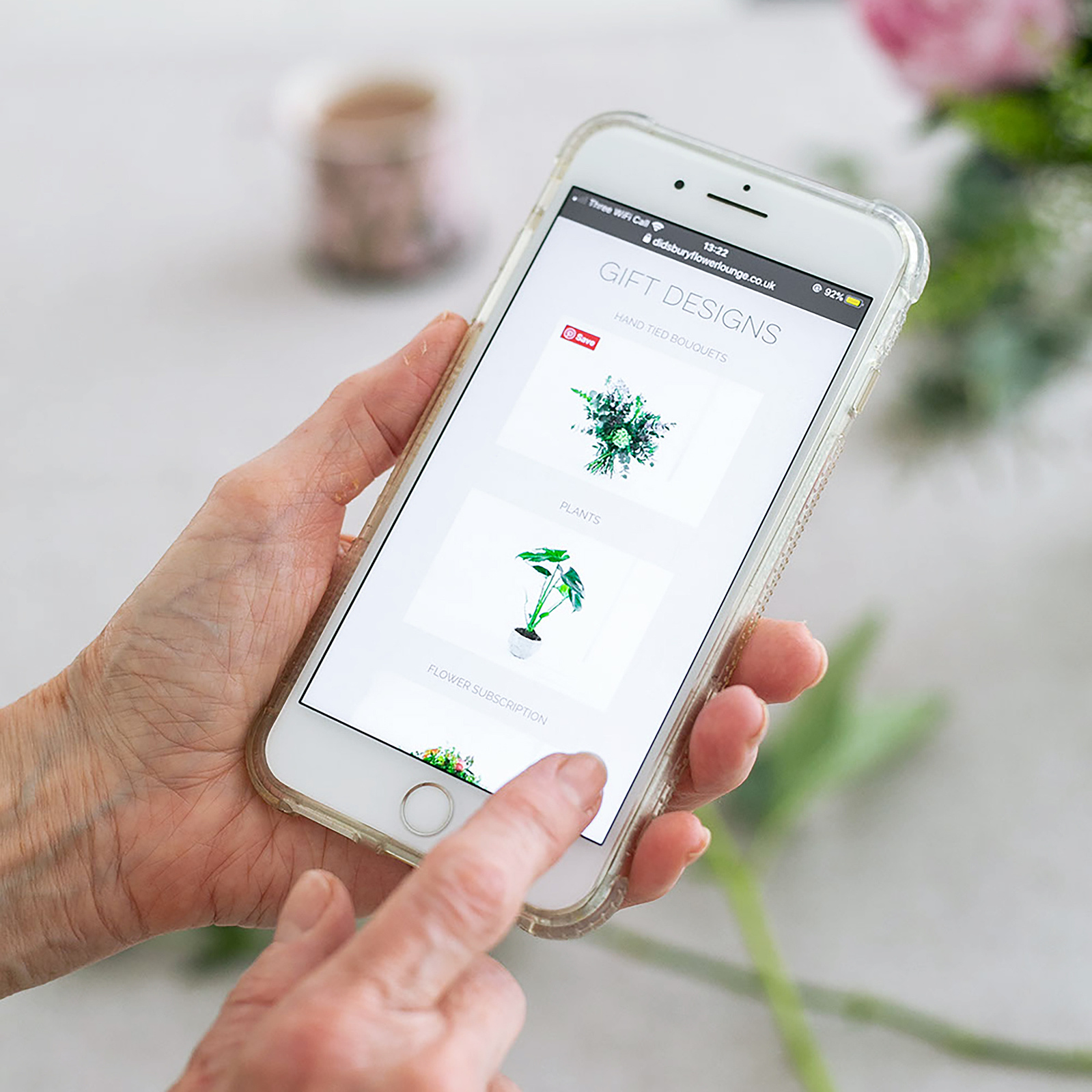 hands holding a mobile phone with images of flowers on it. Product photography by Georgie Glass, Manchester photographer.