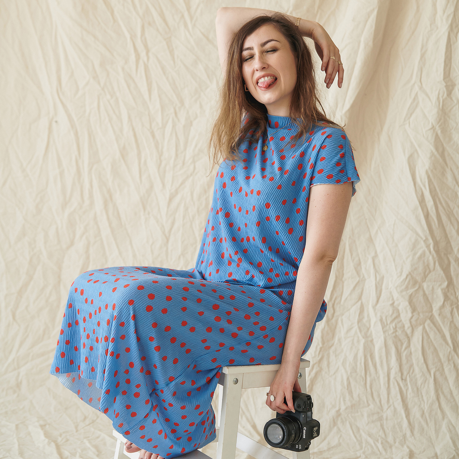 Georgie Glass posing on a stool, holding her camera. Portrait photography by Georgie Glass, Manchester photographer.