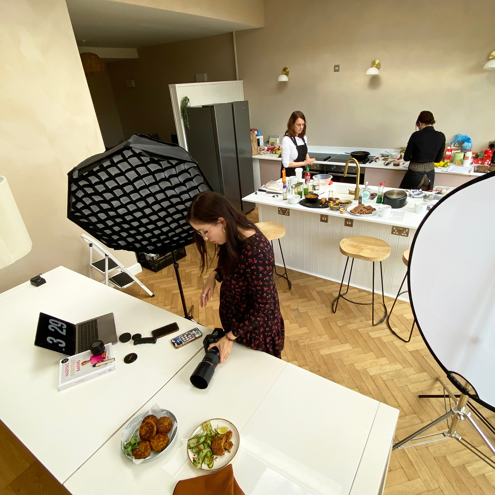Georgie Glass Photography image of a photography shoot in action. three women working in a kitchen with photography equipment. Manchester photographer