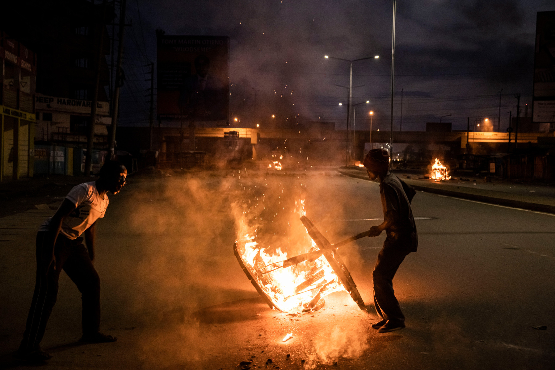 KISUMU, KENYA - AUGUST 15: People burn objects in the road as police fire tear gas as people protest after election results were announced on August 15, 2022 in Kisumu, Kenya. Some protesters could be heard shouting “No Raila, no peace” as they threw ston