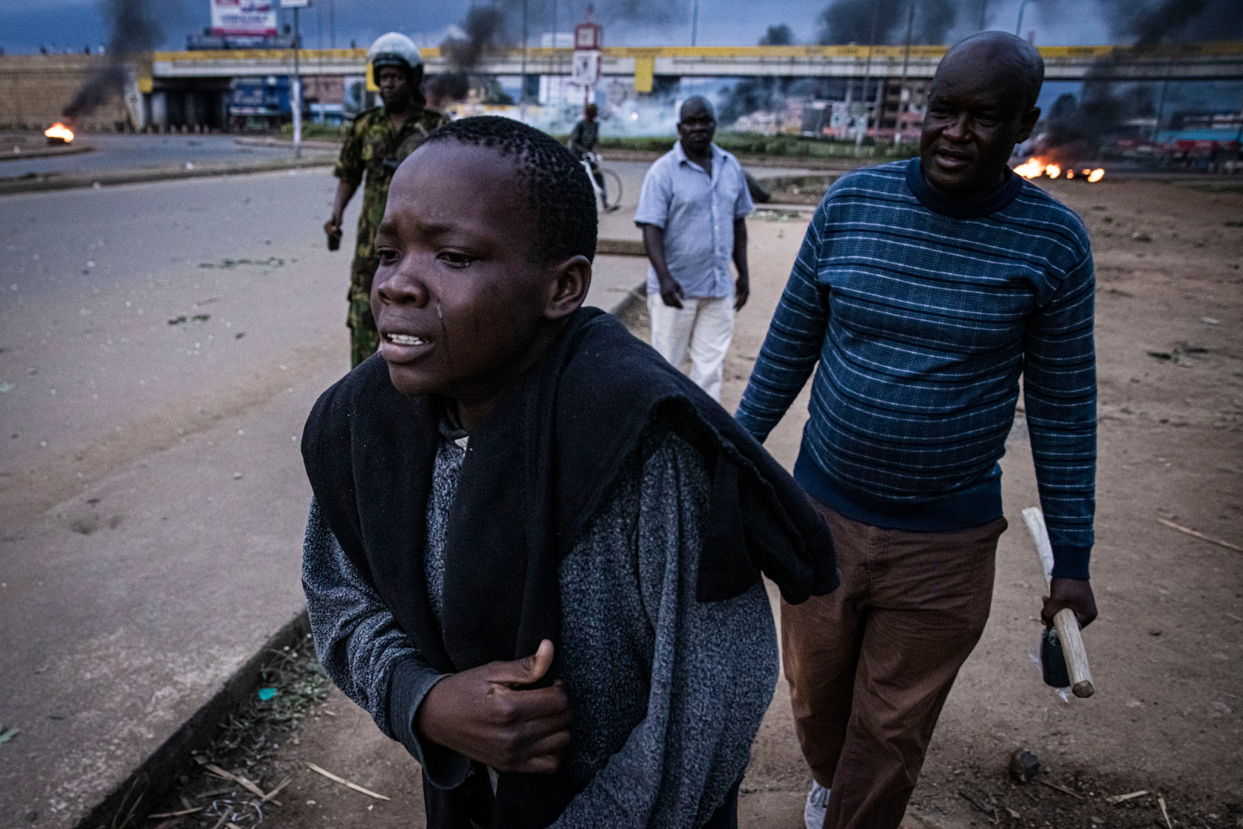 KISUMU, KENYA - AUGUST 15: A young person cries as police fire tear gas and as people protest after election results were announced on August 15, 2022 in Kisumu, Kenya. Some protesters could be heard shouting “No Raila, no peace” as they threw stones and