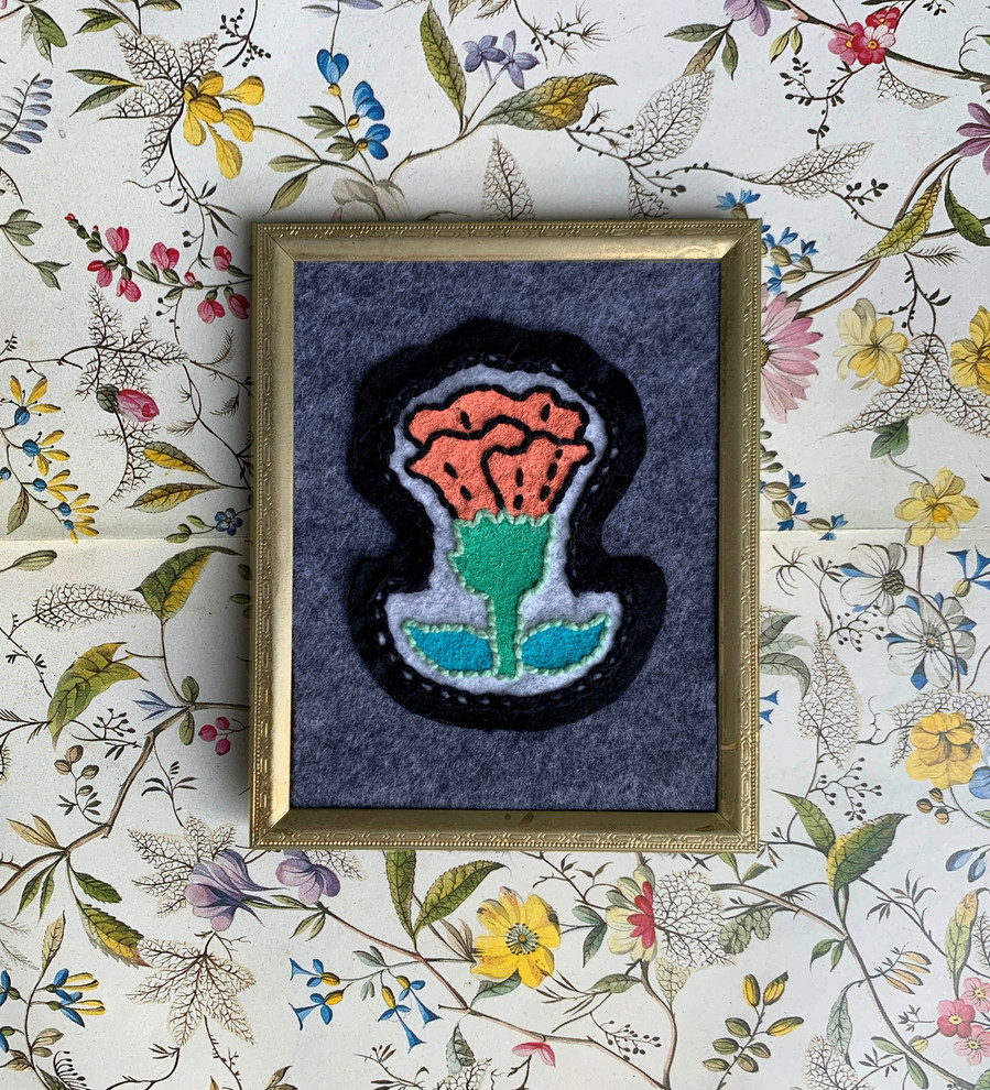 picture of a carnation embroidered patch in a gold frame on a patterned background