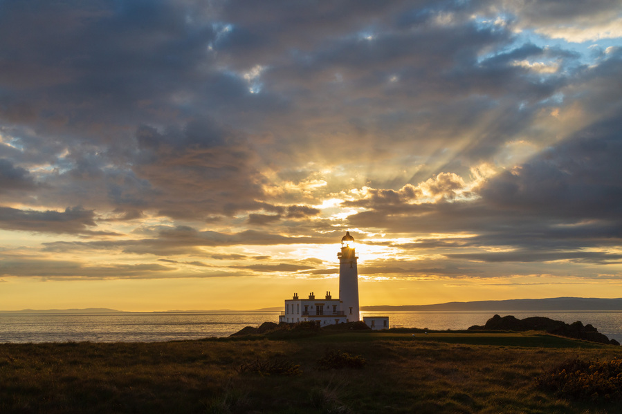 Iconic Turnberry Lighthouse with setting sun shining through the top of the lighthouse.
