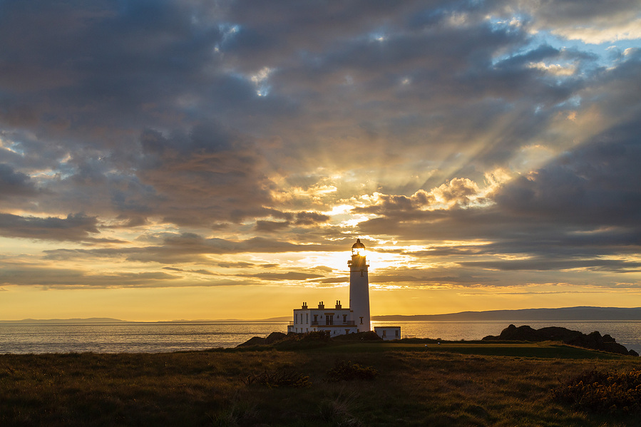 Iconic Turnberry Lighthouse with setting sun shining through the top of the lighthouse.
