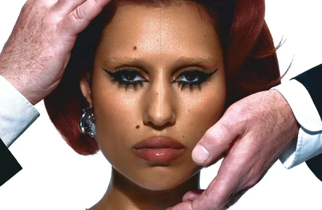 A spread of an image of Raye's face close-up framed by two masculine hands.