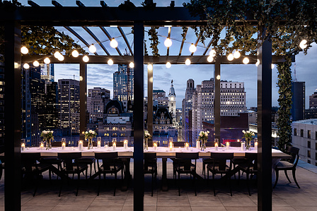 Luxury Dining at The Atlantic Building, Philadelphia - Basel Almisshal captures a luxurious dining setting at The Atlantic Building, offering a breathtaking view of City Hall at dusk. The soft evening light enhances the sophisticated ambiance, creating an
