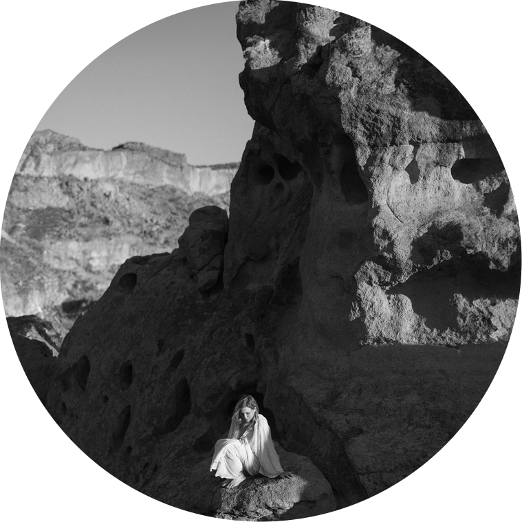 A bride during an adventure elopement, sitting on a rock in a circular frame, in the rocky national area of Western Texas.