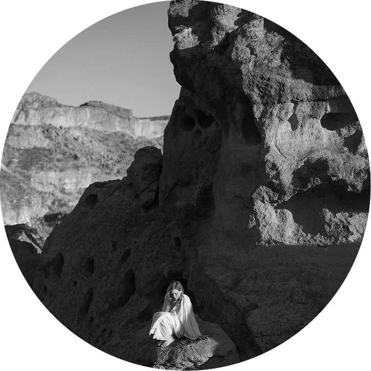 A bride during an adventure elopement, sitting on a rock in a circular frame, in the rocky national area of Western Texas.
