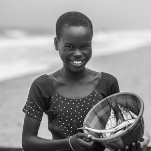 ​girl from a community of fishermen in Lagos, carries a bowl of fish for the day’s meal