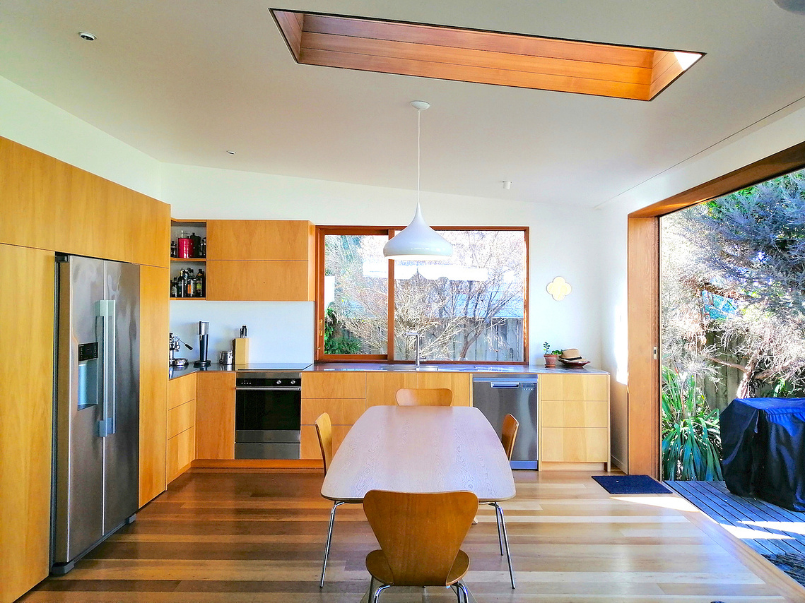 Light filled modern kitchen with timber joinery and open planning and sliding door to garden 