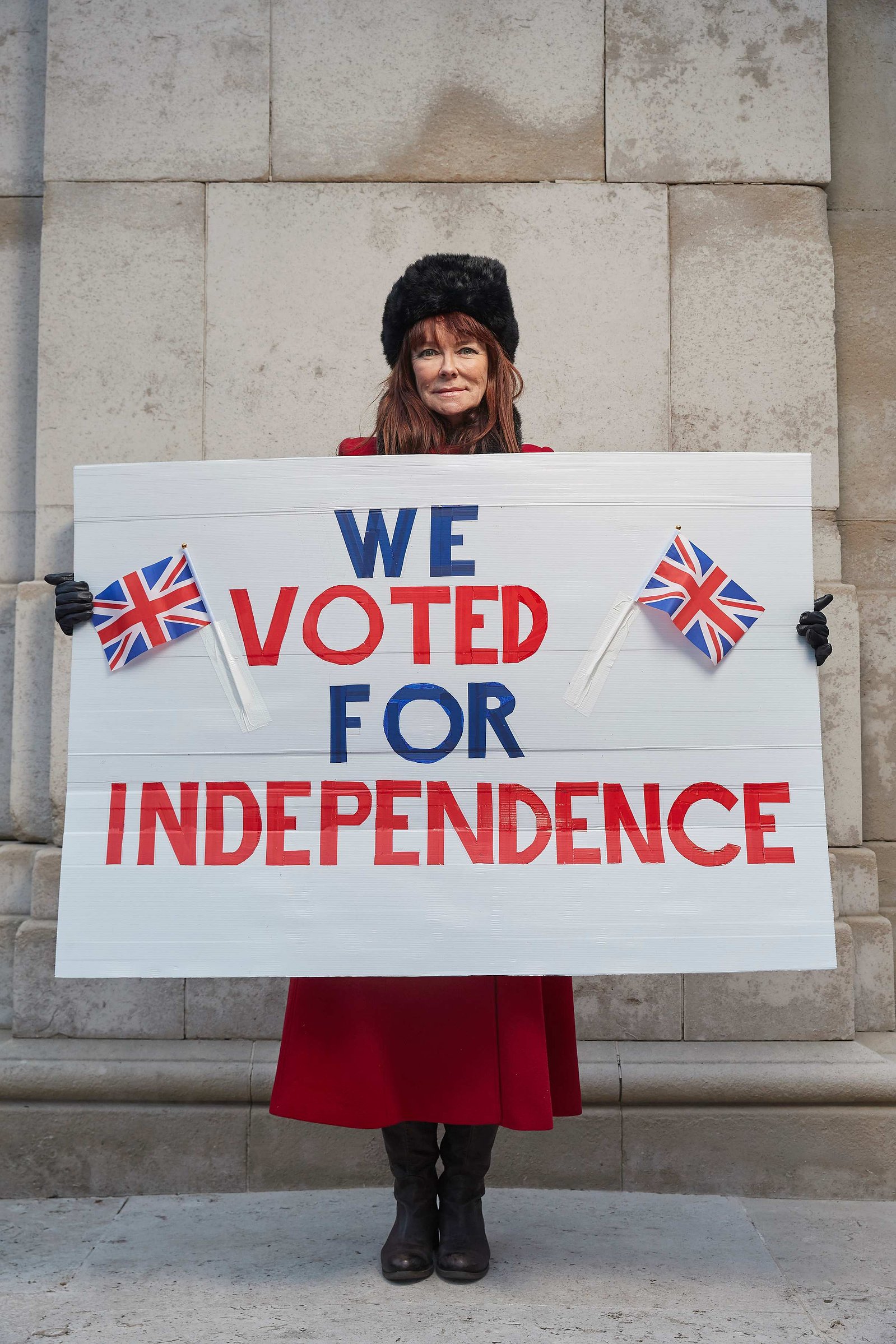 A portrait of Penelope Becker, a leaver and strong Brexit supporter photographed holding a big pro Brexit placard "we voted for Independence" outside the Houses of Parliament in Westminster, London.