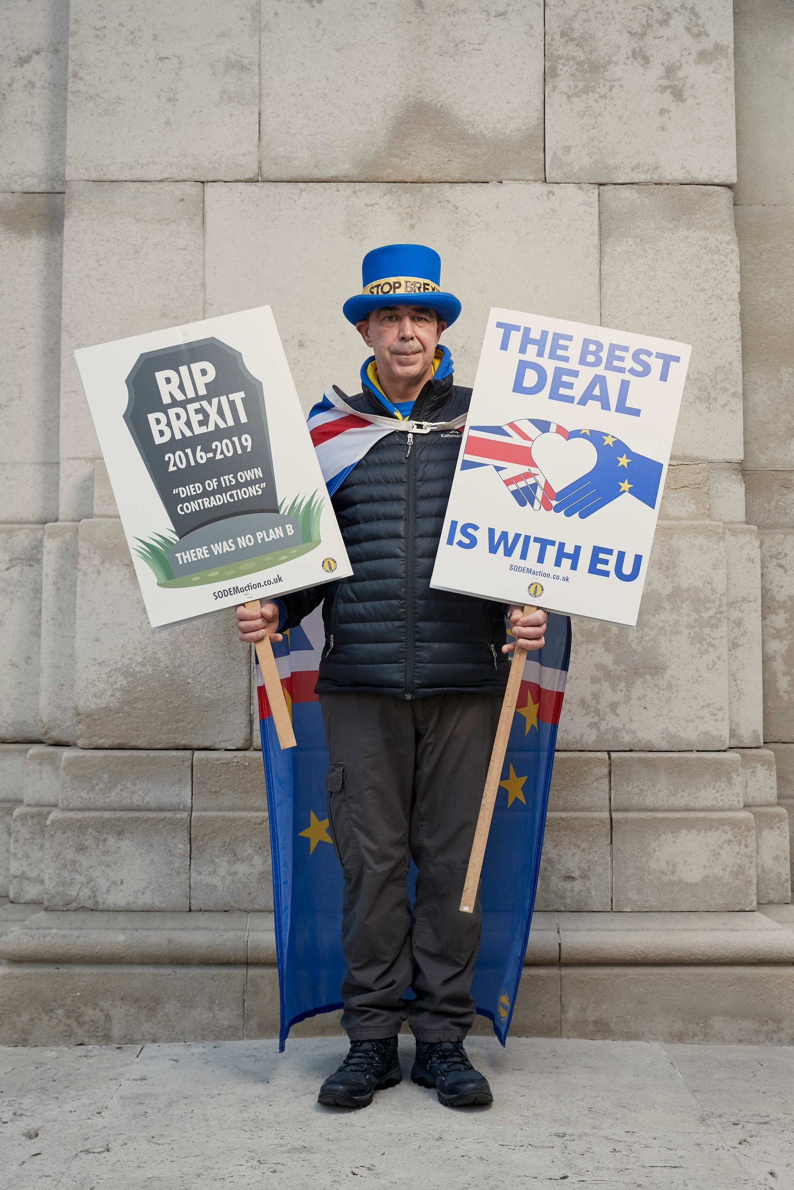 A portrait of Steve Bray, a Remainer, pro European, and anti Brexit protestor photographed dressed in a blue top hat and cloak holding two placards outside the Houses of Parliament in Westminster, London.