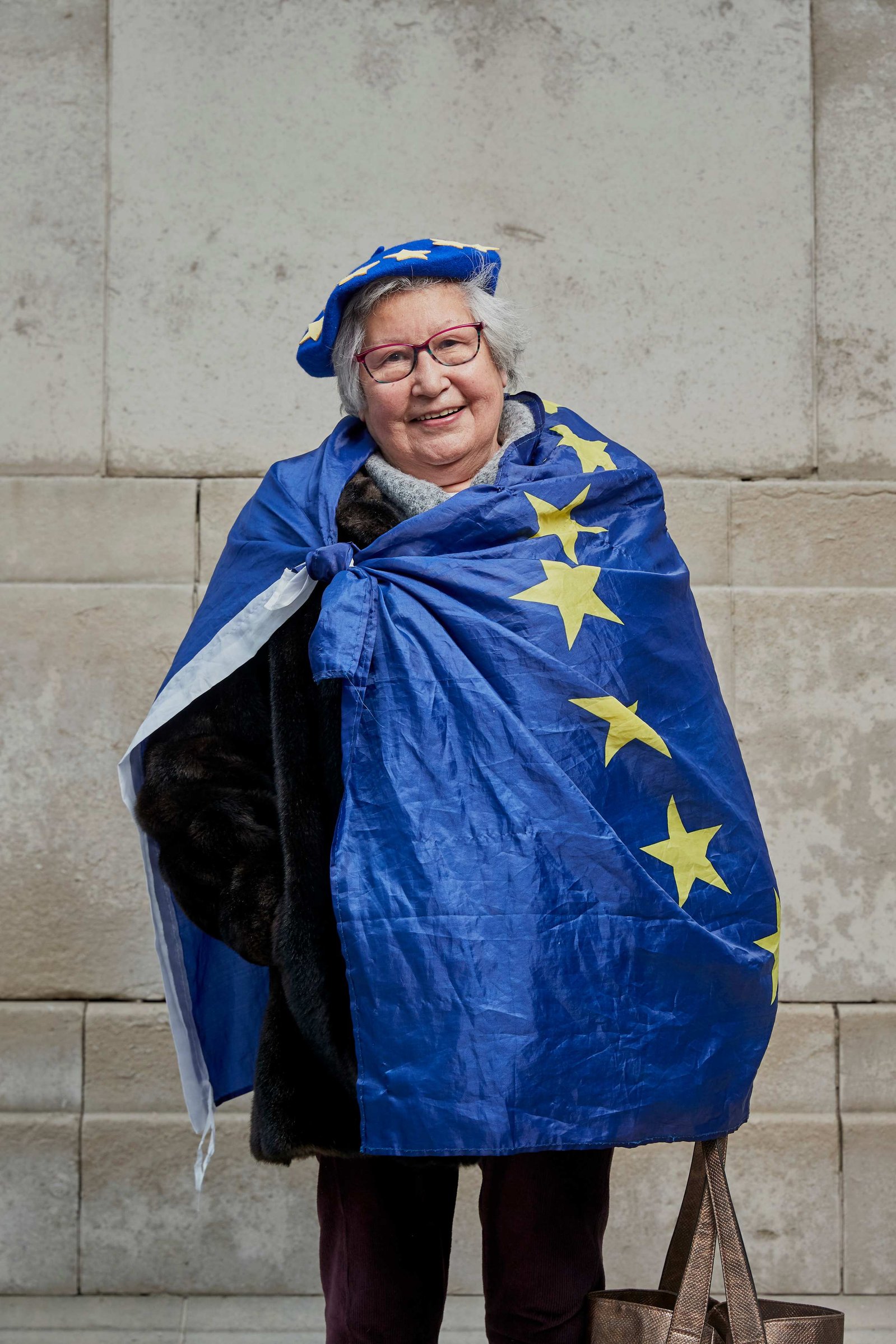 A portrait of Judith Spencer, a Remainer, pro European, and anti Brexit protestor photographed dressed in a blue European Flag and wearing a Blue Beret outside the Houses of Parliament in Westminster, London.